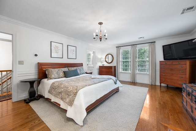 bedroom with a chandelier, wood finished floors, ornamental molding, and baseboards