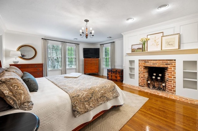 bedroom featuring crown molding, a chandelier, wood finished floors, a fireplace, and recessed lighting