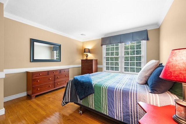 bedroom with wood finished floors, ornamental molding, and baseboards