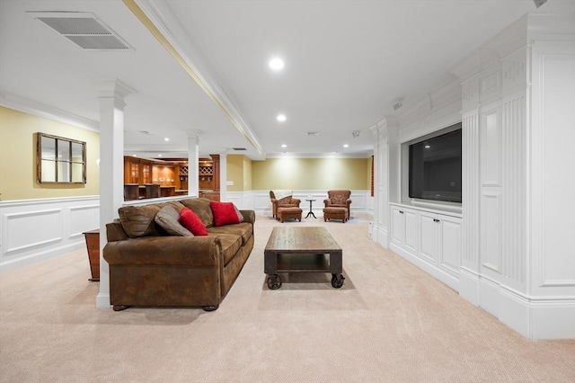 living area with decorative columns, a decorative wall, ornamental molding, carpet, and recessed lighting