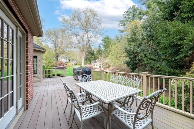wooden terrace with outdoor dining area and a grill