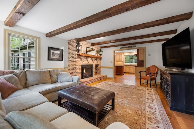 living area featuring a fireplace, light wood-style floors, and beam ceiling
