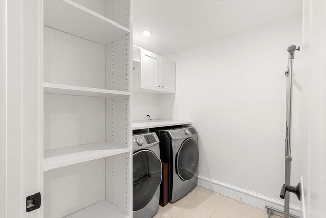 42 Coolidge St Unit 42, Brookline, MA 02446 - washroom with cabinet space, washing machine and clothes dryer, light tile patterned floors, and baseboards