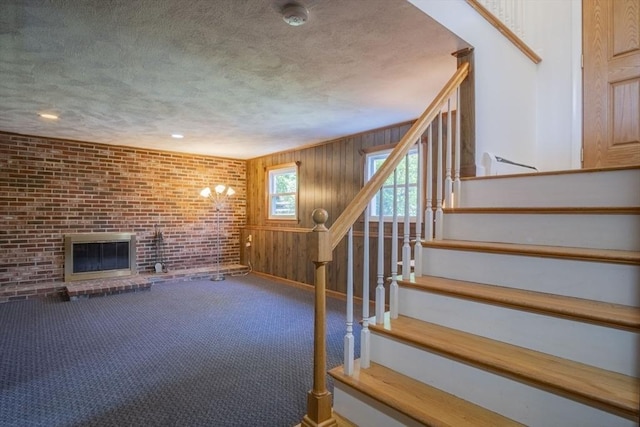 6 Marshall Rd, Beverly, MA 01915 - unfurnished living room featuring stairs, a brick fireplace, a textured ceiling, carpet flooring, and brick wall