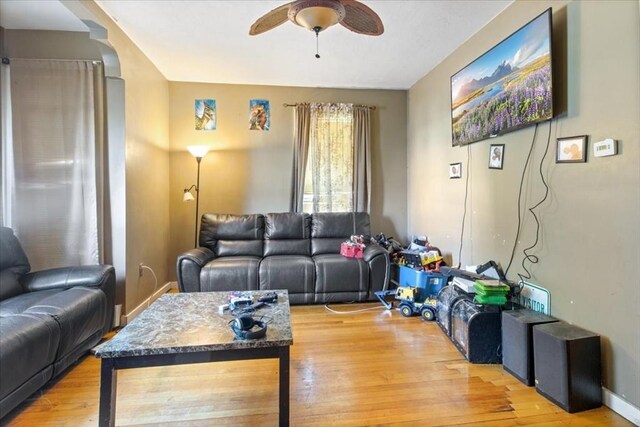 living room featuring wood finished floors, baseboards, and ceiling fan
