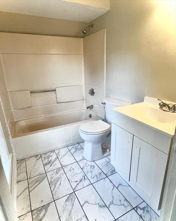 bathroom featuring marble finish floor, toilet, vanity, and bathing tub / shower combination