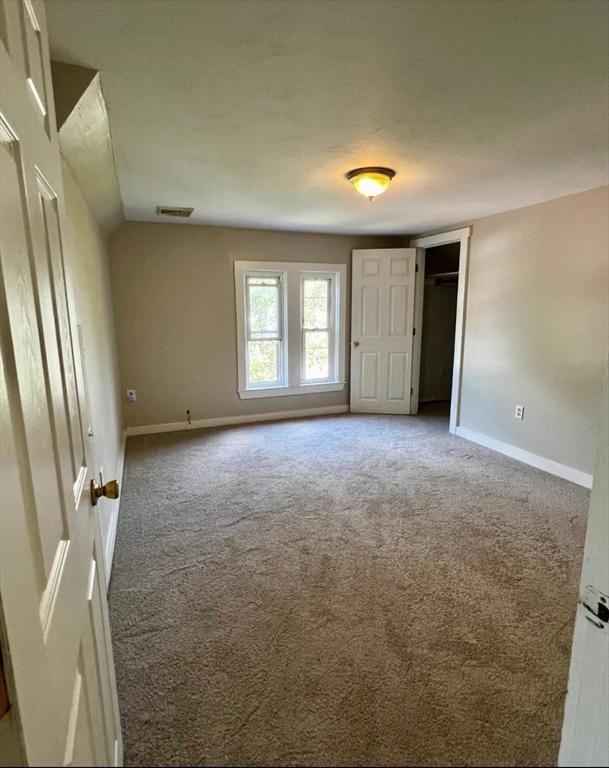 empty room featuring visible vents, baseboards, carpet, and lofted ceiling