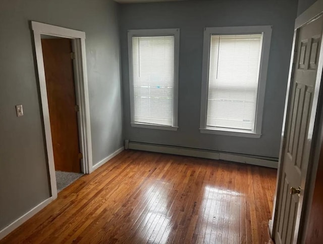 unfurnished bedroom featuring wood-type flooring, baseboards, and baseboard heating