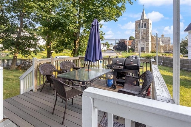 wooden terrace featuring a lawn, fence, and outdoor dining space