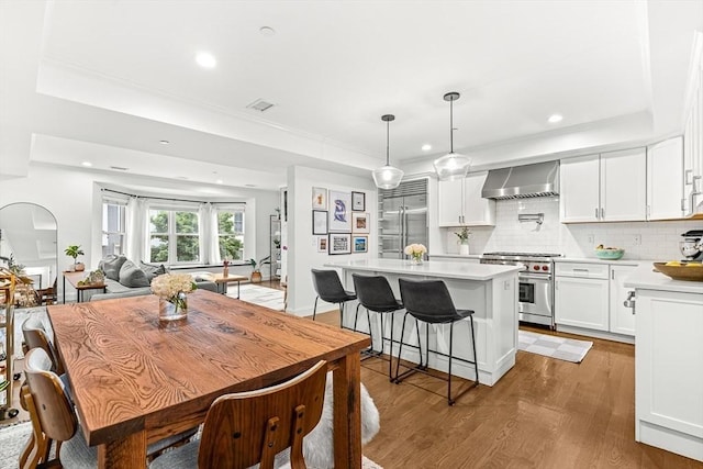 280 W 5th St Unit 101, Boston, MA 02127 - kitchen featuring high end appliances, wall chimney range hood, a raised ceiling, a kitchen island, and recessed lighting