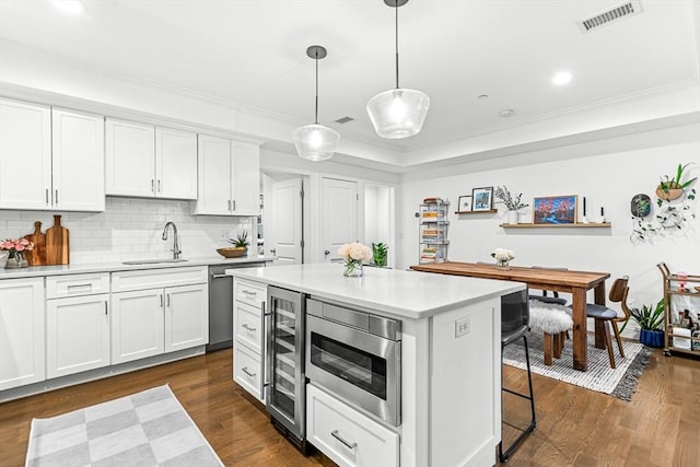 280 W 5th St Unit 101, Boston, MA 02127 - kitchen with wine cooler, appliances with stainless steel finishes, light countertops, white cabinets, and ornamental molding