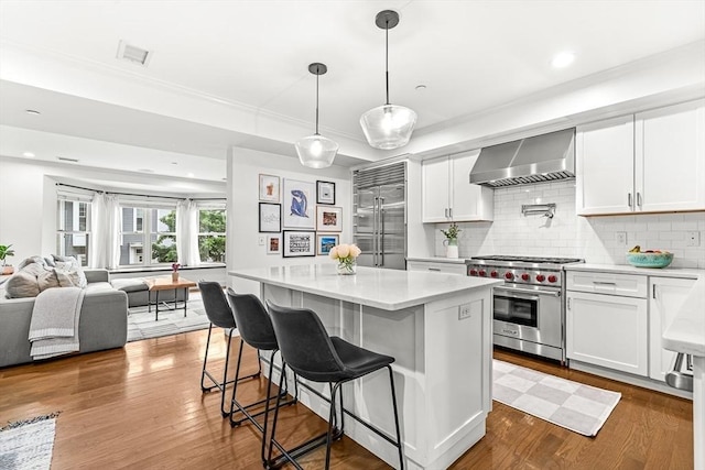 280 W 5th St Unit 101, Boston, MA 02127 - kitchen featuring wall chimney range hood, high quality appliances, light countertops, decorative backsplash, and crown molding