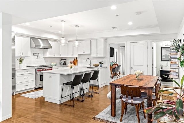 280 W 5th St Unit 101, Boston, MA 02127 - kitchen with high end range, wall chimney range hood, light countertops, backsplash, and recessed lighting