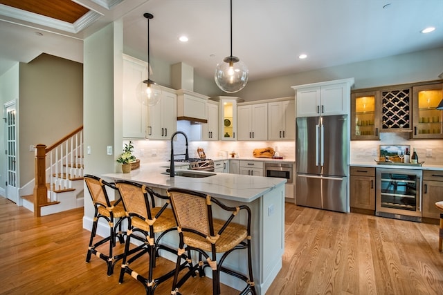 kitchen featuring beverage cooler, white cabinets, kitchen peninsula, appliances with stainless steel finishes, and decorative light fixtures