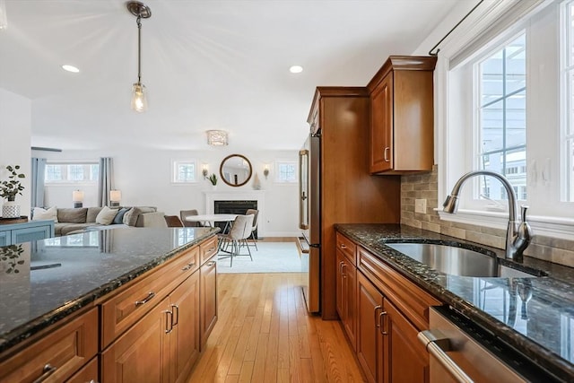 kitchen featuring appliances with stainless steel finishes, pendant lighting, sink, dark stone countertops, and decorative backsplash