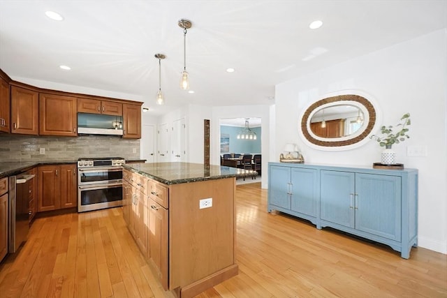 kitchen featuring light hardwood / wood-style flooring, hanging light fixtures, stainless steel appliances, a kitchen island, and decorative backsplash