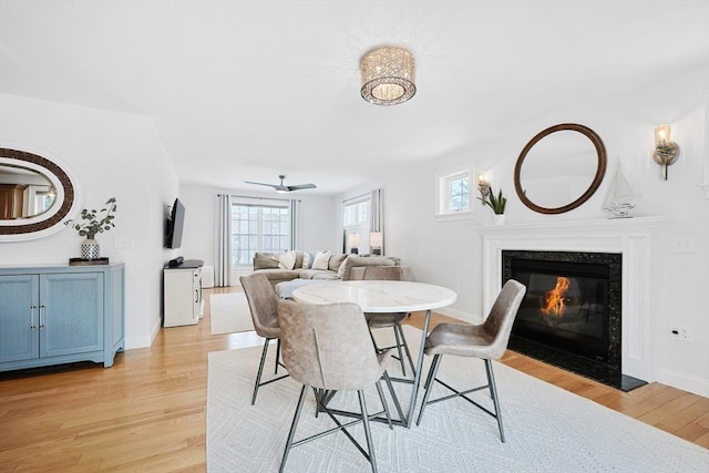 dining room with a high end fireplace and light hardwood / wood-style floors