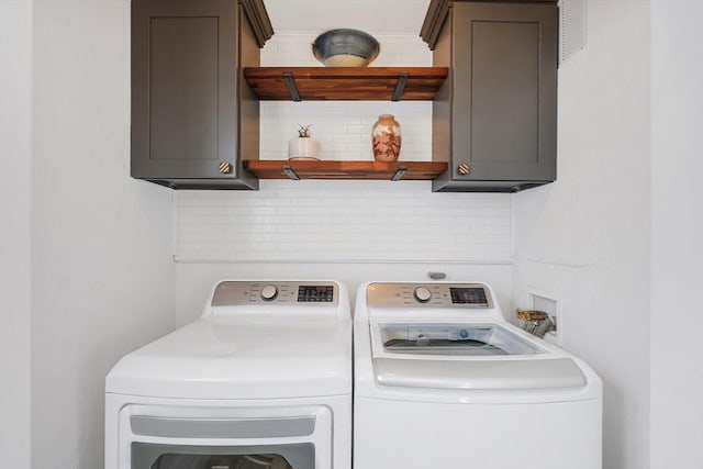 clothes washing area with washing machine and dryer and cabinets