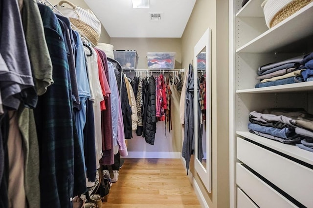 walk in closet with light hardwood / wood-style floors