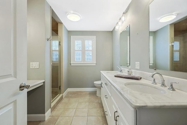 bathroom featuring tile patterned flooring, vanity, a shower with shower door, and toilet