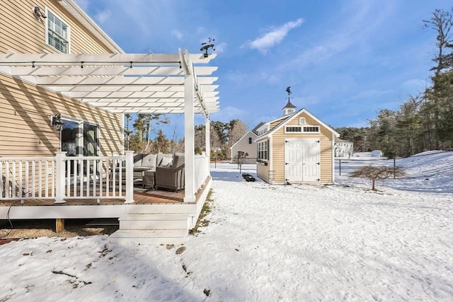 yard covered in snow with a storage shed, a pergola, and a wooden deck