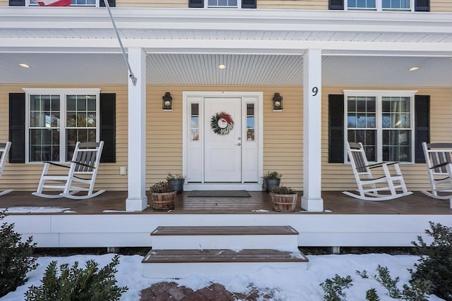 snow covered property entrance with covered porch