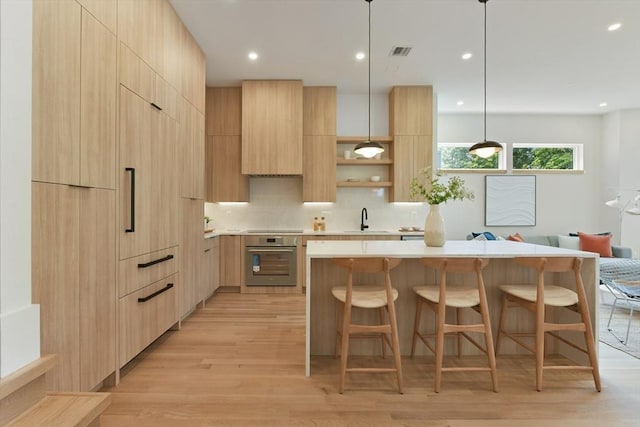 21 Eastman Rd Unit 0, Somerville, MA 02143 - kitchen with modern cabinets, stainless steel oven, light brown cabinetry, light countertops, and light wood-type flooring