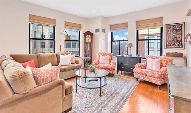 living room featuring wood-type flooring, recessed lighting, a healthy amount of sunlight, and visible vents