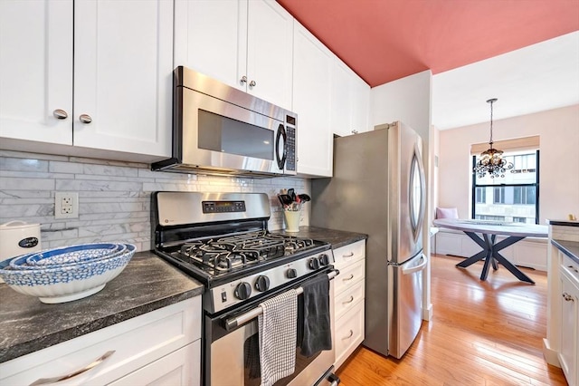 kitchen featuring white cabinetry, a chandelier, light wood-style flooring, backsplash, and stainless steel appliances