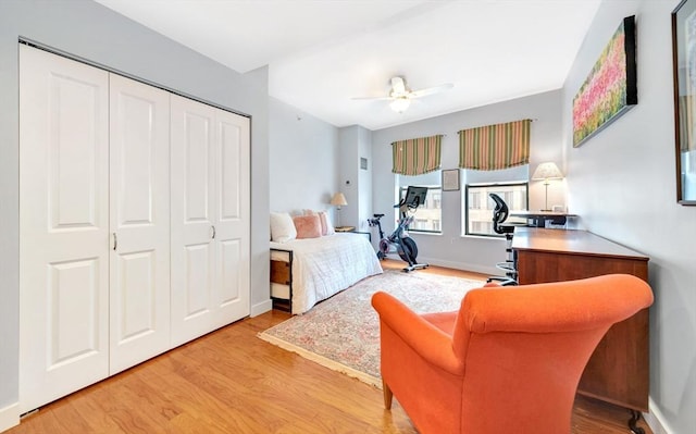 bedroom with a closet, a ceiling fan, baseboards, and light wood-type flooring