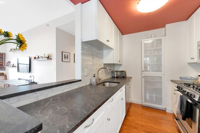 kitchen with a sink, tasteful backsplash, stainless steel appliances, and dark stone countertops