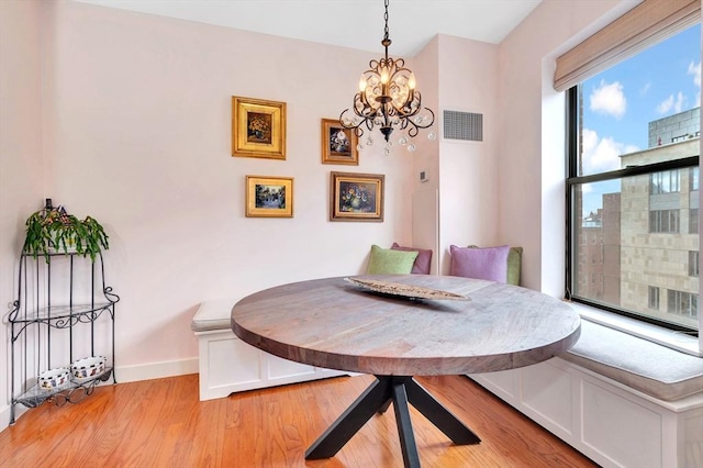 dining room with breakfast area, a chandelier, baseboards, light wood-type flooring, and visible vents