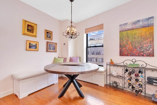 dining area featuring baseboards, breakfast area, light wood-type flooring, and a notable chandelier
