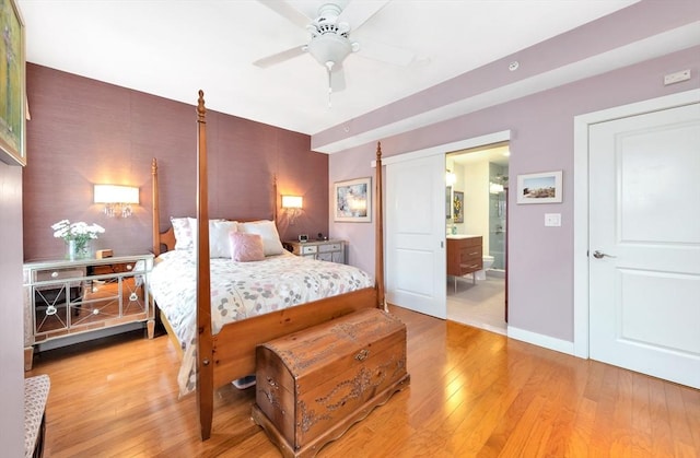 bedroom featuring baseboards, wallpapered walls, an accent wall, and light wood-style floors