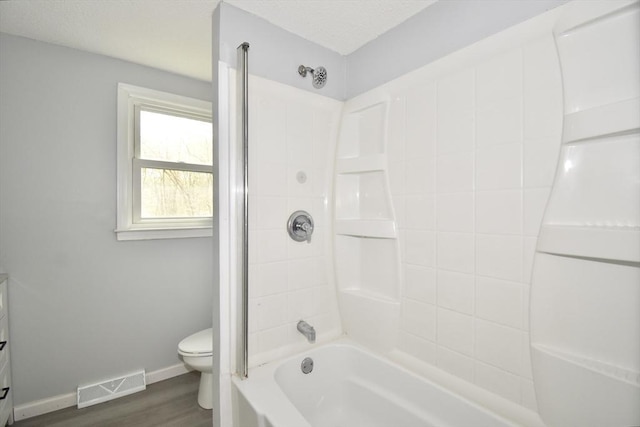 bathroom with shower / bath combination, visible vents, wood finished floors, baseboards, and toilet
