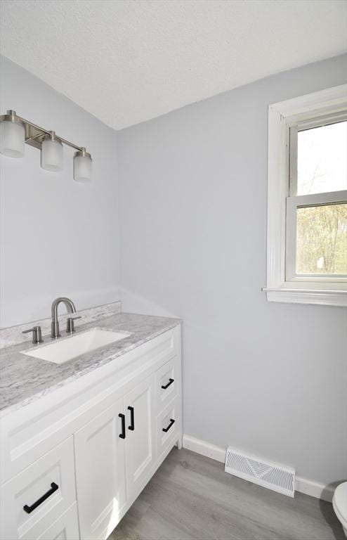 bathroom featuring baseboards, wood finished floors, and visible vents