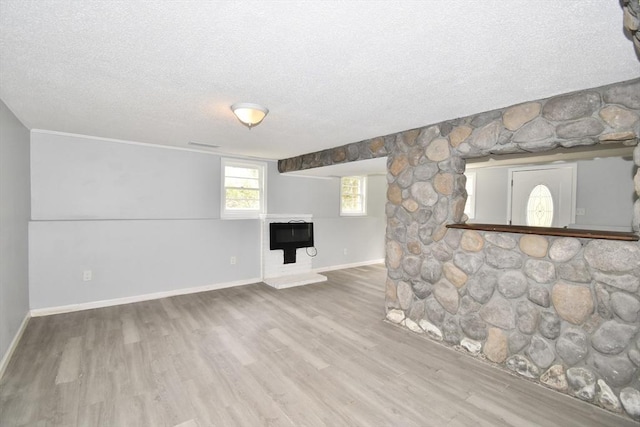 unfurnished living room featuring baseboards, a textured ceiling, and wood finished floors
