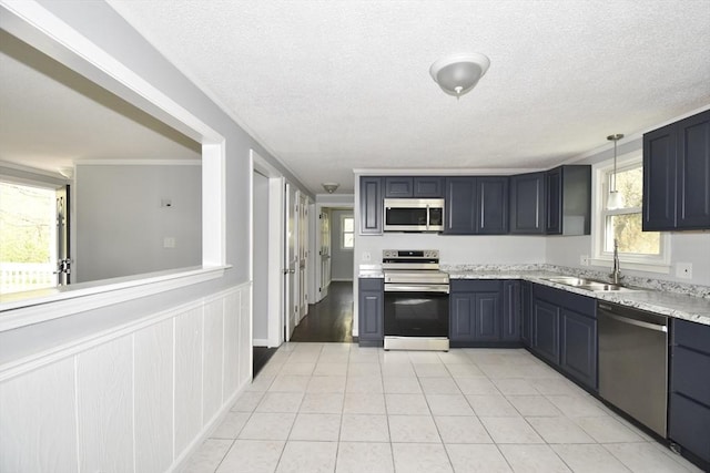 kitchen featuring light stone countertops, a textured ceiling, a sink, appliances with stainless steel finishes, and light tile patterned floors