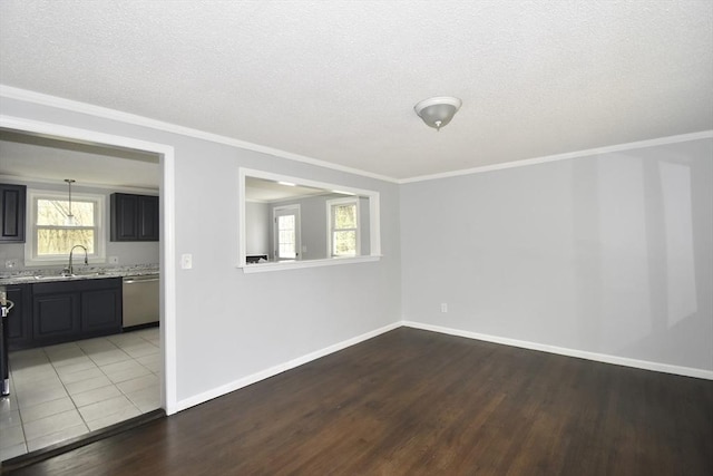 unfurnished room with crown molding, baseboards, a textured ceiling, and wood finished floors