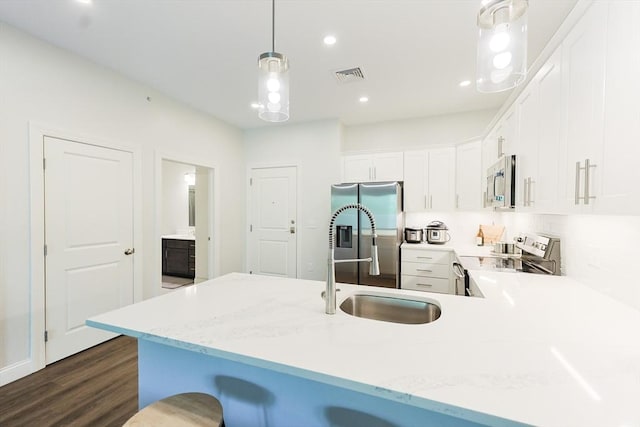 kitchen featuring appliances with stainless steel finishes, a peninsula, dark wood-style floors, white cabinets, and a sink