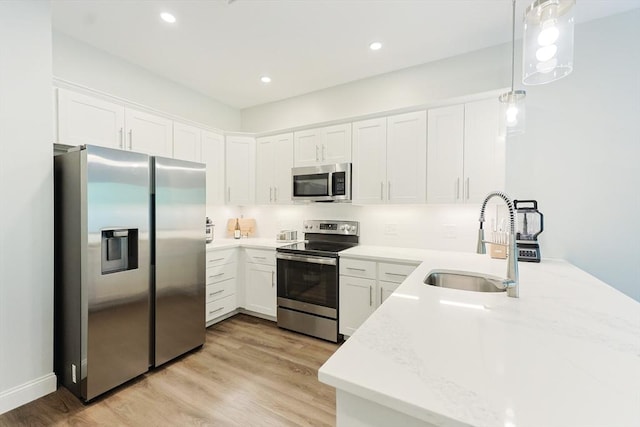 kitchen featuring appliances with stainless steel finishes, a sink, white cabinets, light countertops, and recessed lighting