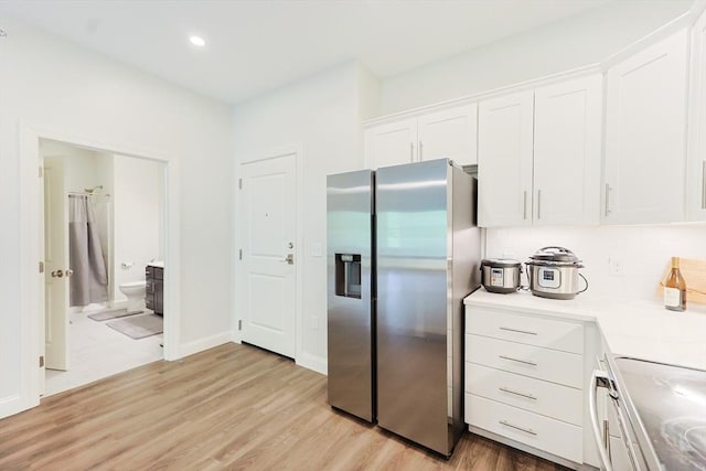kitchen with stainless steel refrigerator with ice dispenser, white cabinets, electric range, decorative backsplash, and light wood-style flooring