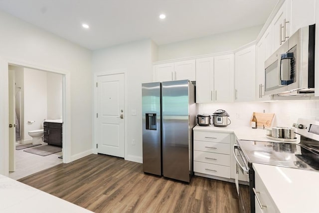 kitchen with stainless steel appliances, white cabinetry, light countertops, dark wood-style floors, and recessed lighting