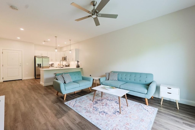 living area featuring wood finished floors, baseboards, a ceiling fan, and recessed lighting