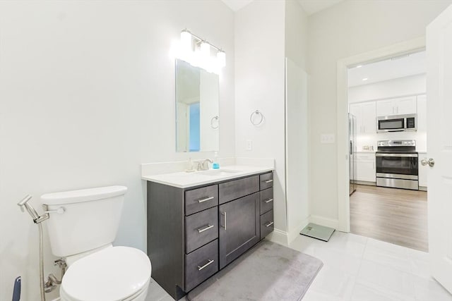 bathroom with toilet, tile patterned flooring, vanity, and baseboards