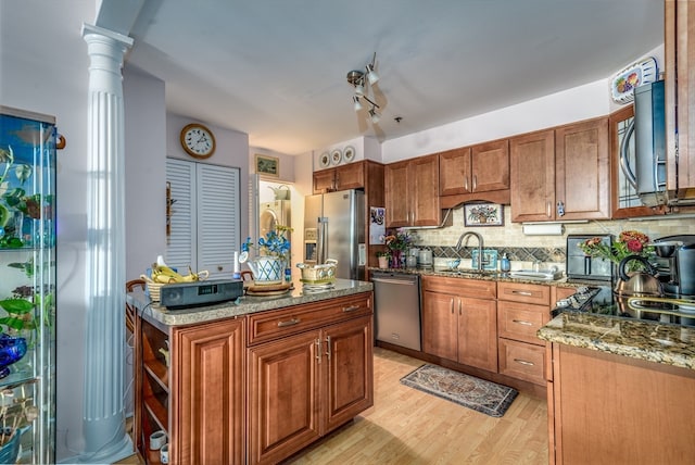 kitchen featuring sink, tasteful backsplash, stainless steel appliances, decorative columns, and light hardwood / wood-style floors