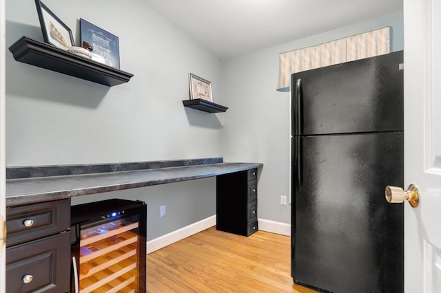 kitchen with black refrigerator, dark brown cabinets, beverage cooler, and light wood-type flooring