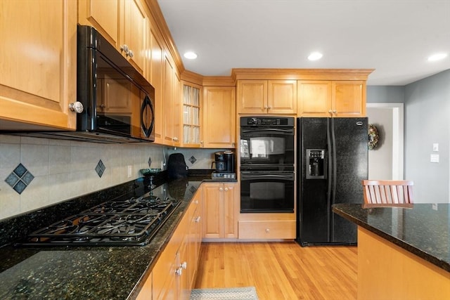 kitchen featuring decorative backsplash, dark stone counters, light hardwood / wood-style flooring, and black appliances