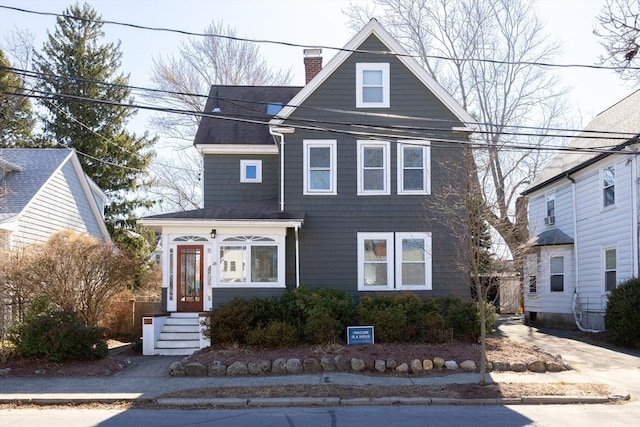 view of front facade with a shingled roof and a chimney