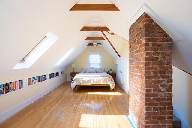 unfurnished bedroom with lofted ceiling with skylight, hardwood / wood-style flooring, and baseboards